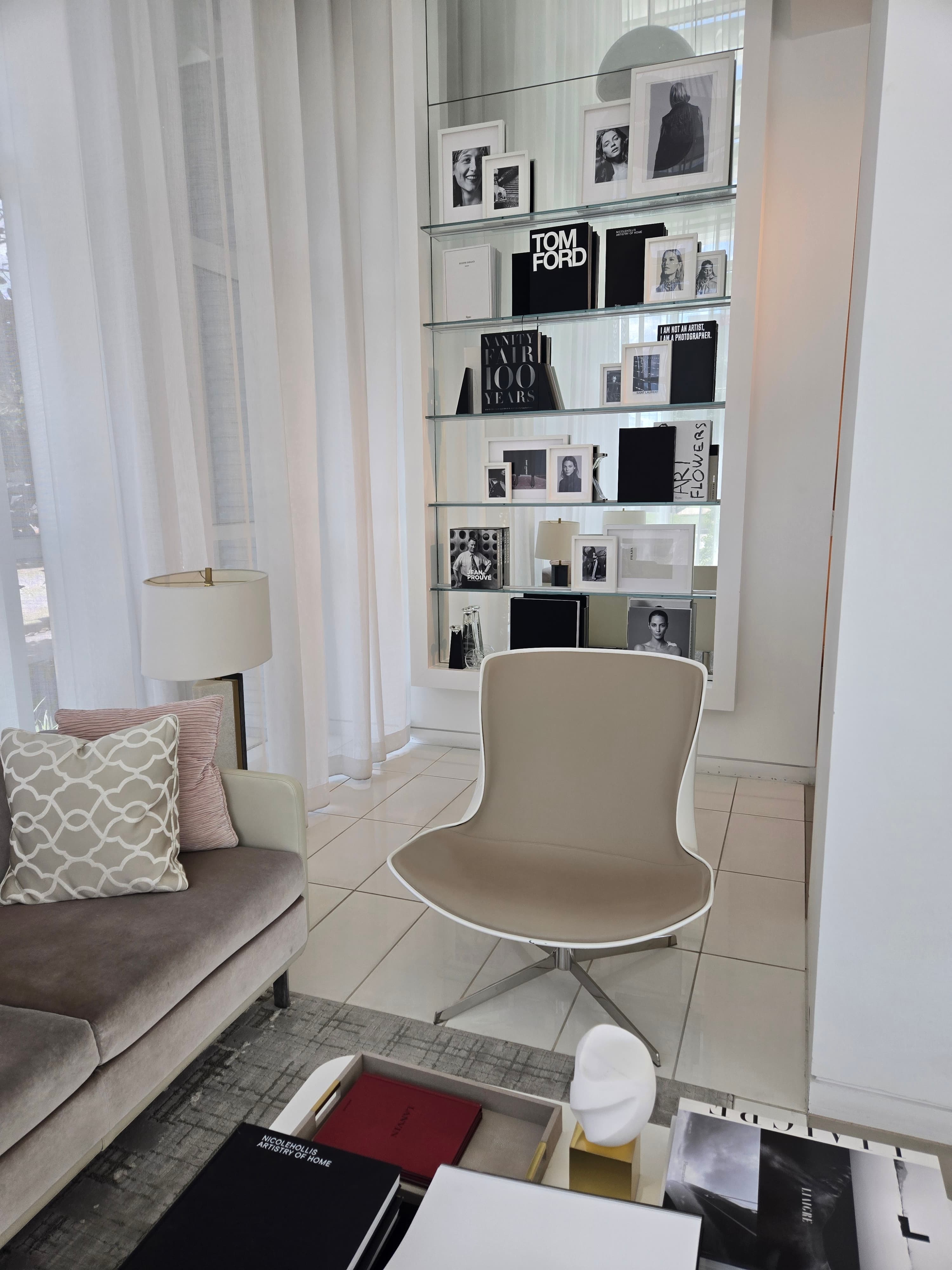 Mirror Mirror waiting area with seating, sheer curtains, and glass shelves displaying art books and photographs.